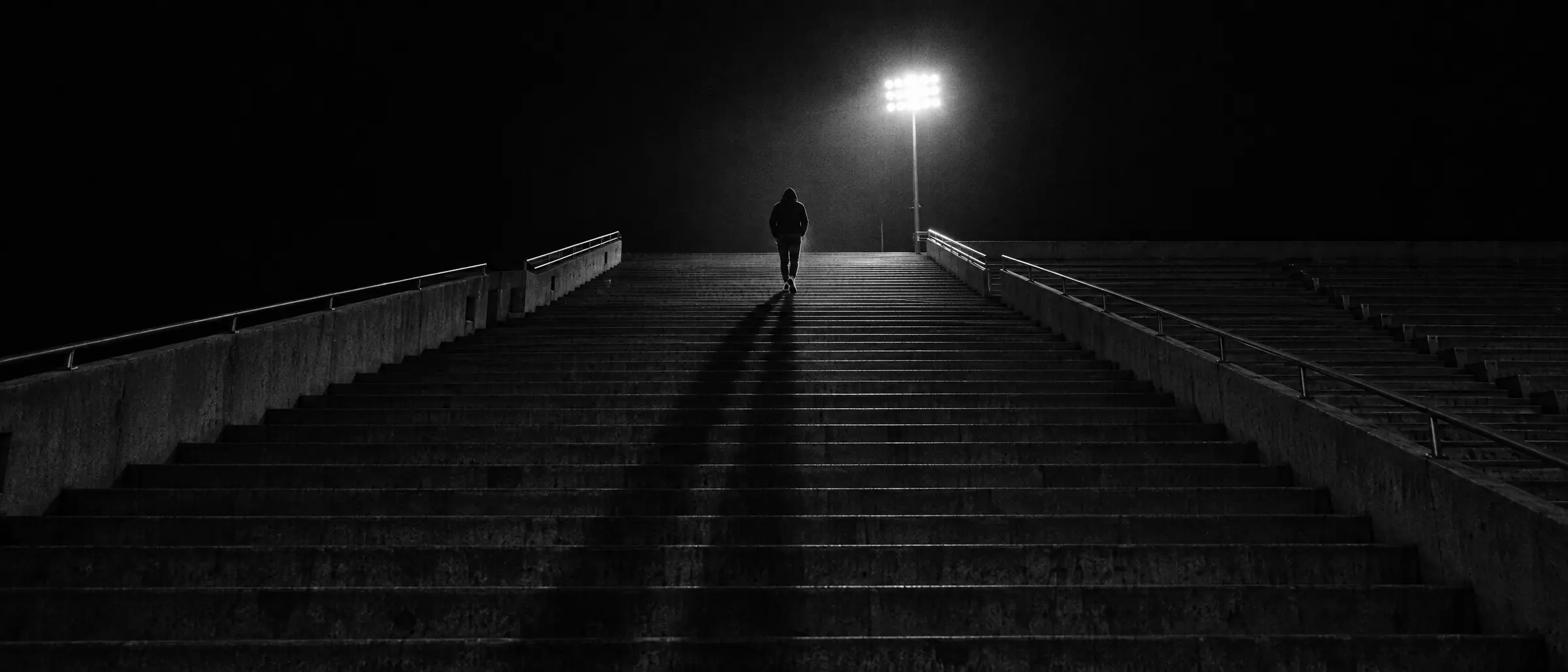 Atleta solo subiendo las gradas de un estadio vacío, de noche